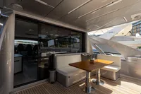 Outdoor seating area on 2021 Pershing 8X yacht with wooden table and cushioned benches.