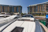 Luxury Pershing 8X yacht docked at marina with modern buildings in background, 2021 model.