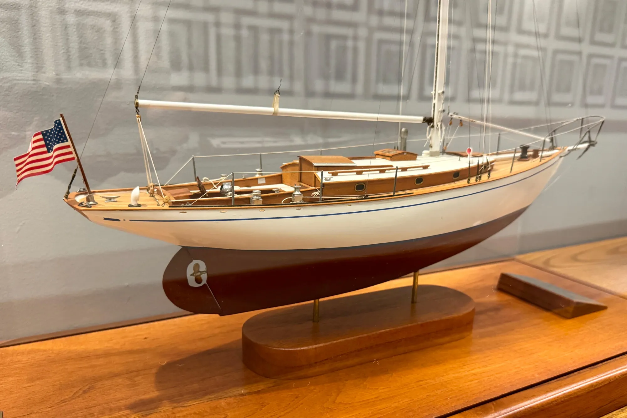 Model of a 1938 Philip Rhodes Cutter sailboat with American flag on display stand.
