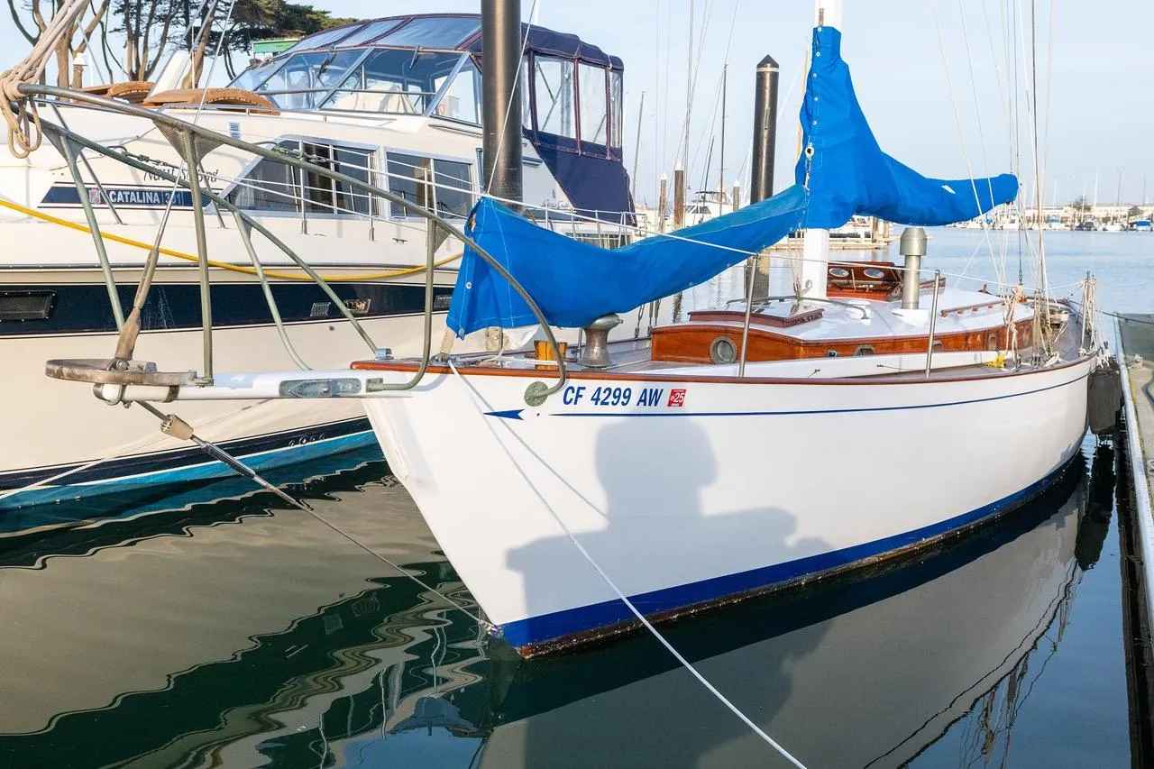1938 Philip Rhodes Cutter sailboat docked with blue covers and wooden details.