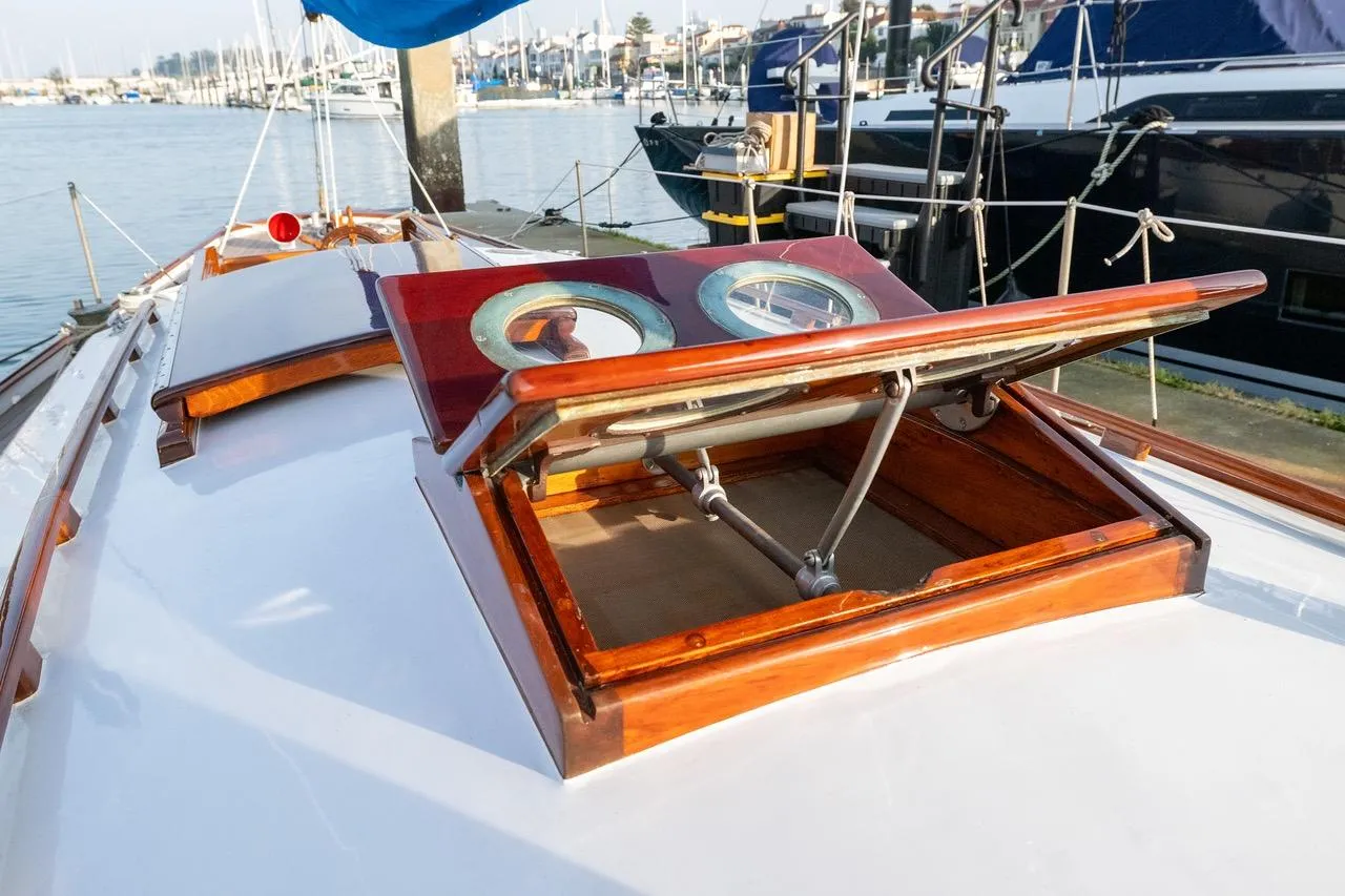 1938 Philip Rhodes Cutter yacht with open wooden hatch, docked in a marina.