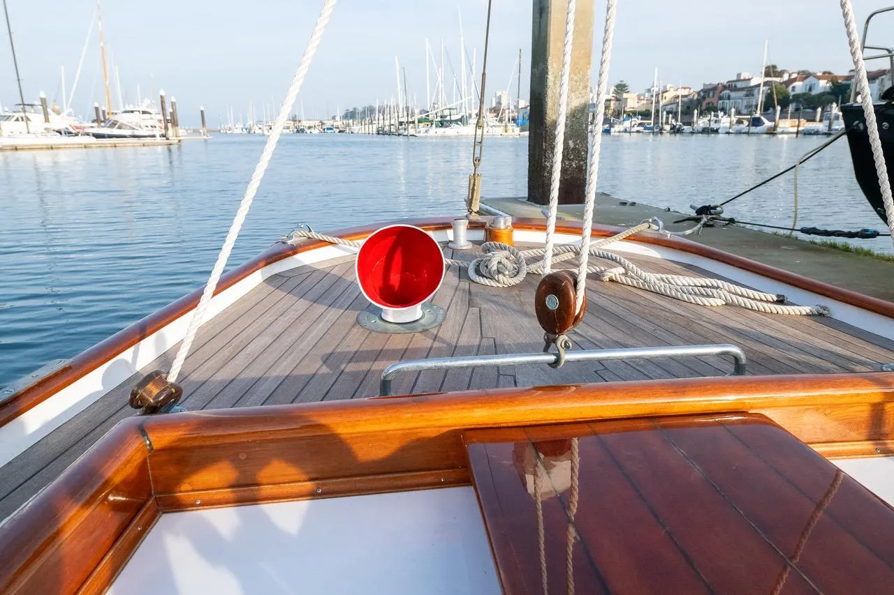1938 Philip Rhodes Cutter sailboat deck with ropes and red vent in a marina.