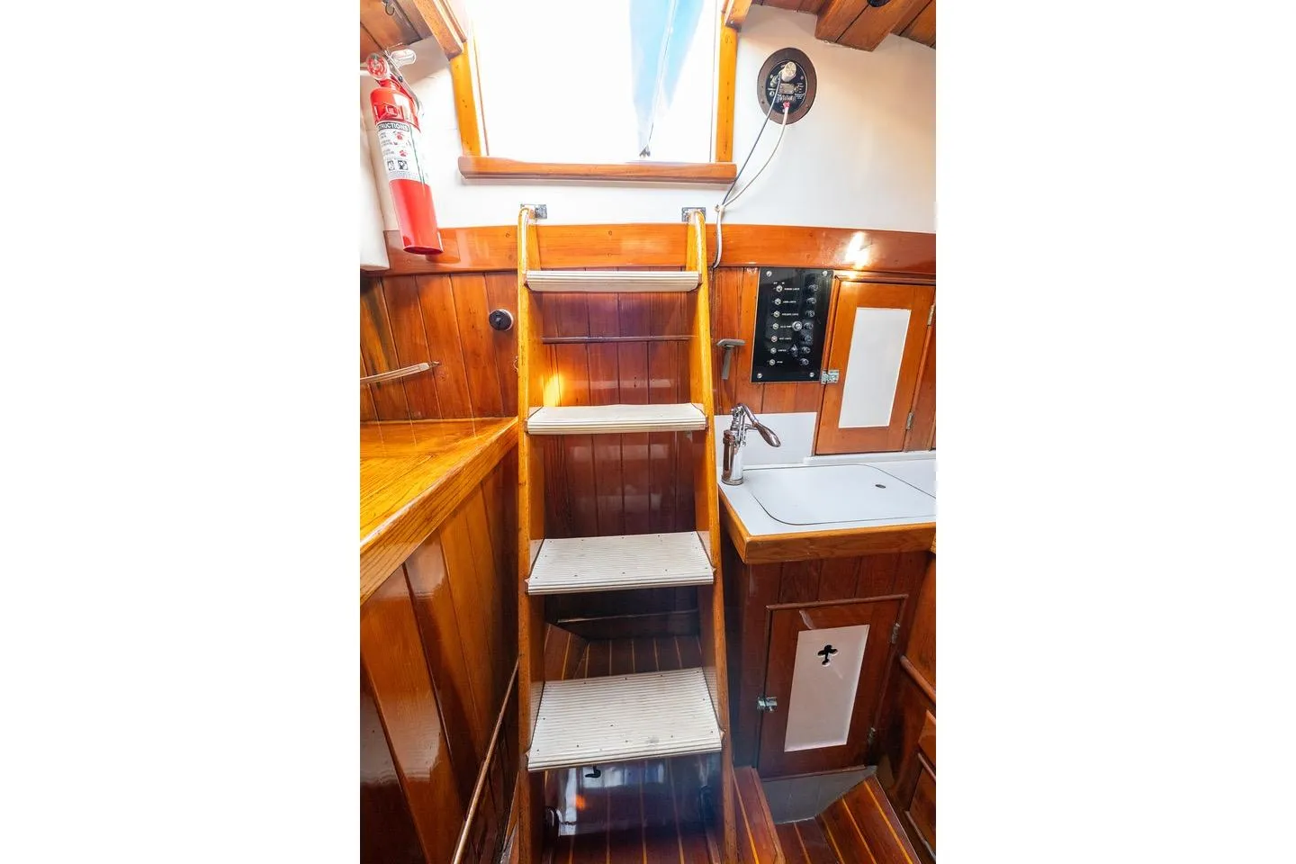 Interior of 1938 Philip Rhodes Cutter, featuring wooden stairs, sink, and fire extinguisher.
