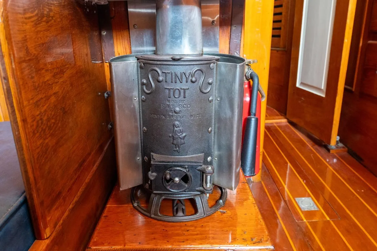 Vintage stove on 1938 Philip Rhodes Cutter boat, featuring wooden interior and classic design.