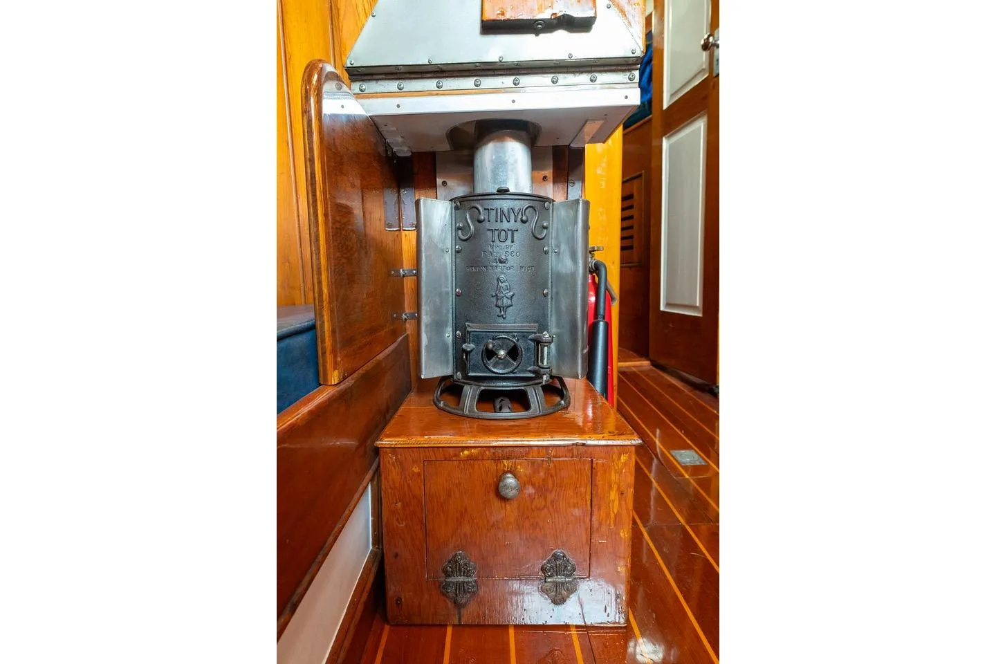 Vintage stove inside 1938 Philip Rhodes Cutter boat, featuring wooden interior and classic design.