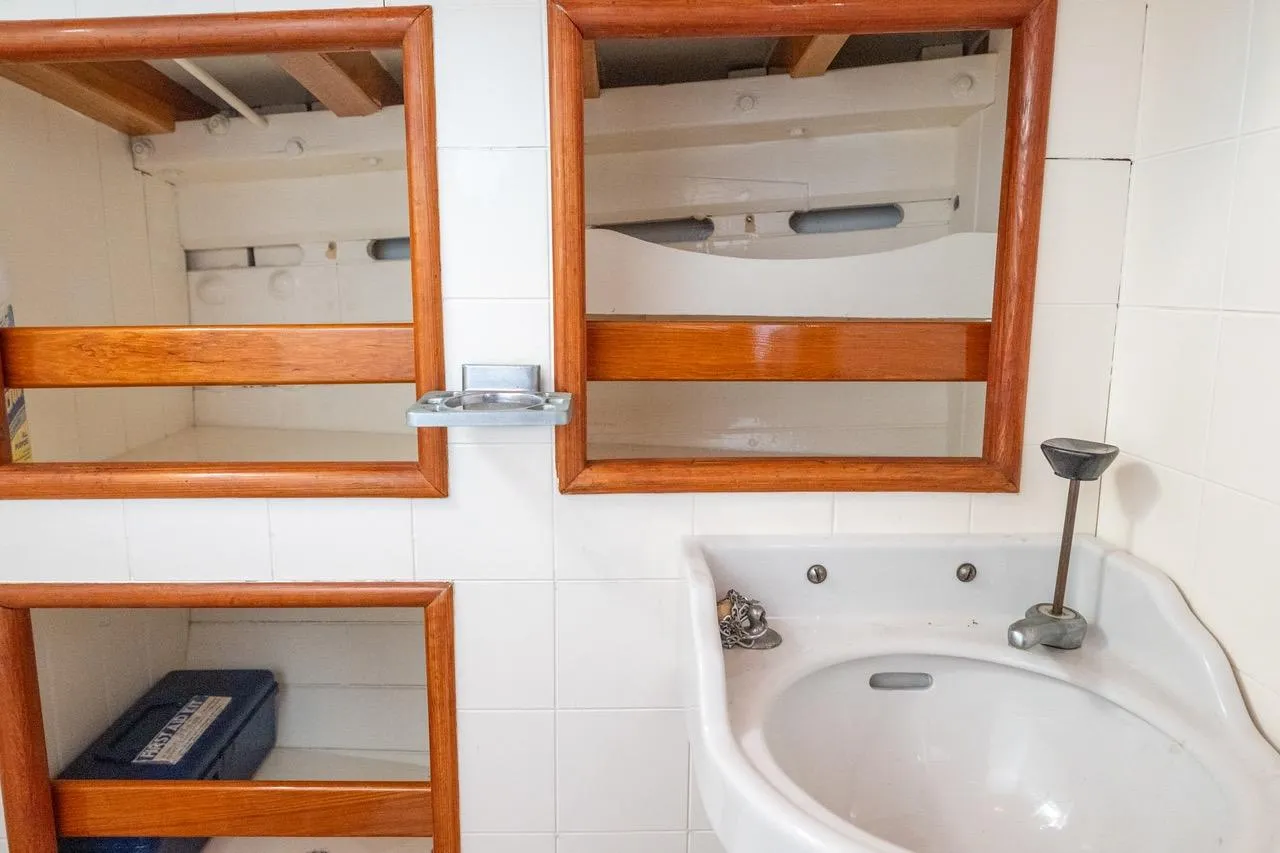 1938 Philip Rhodes Cutter bathroom with wooden shelves and white sink.