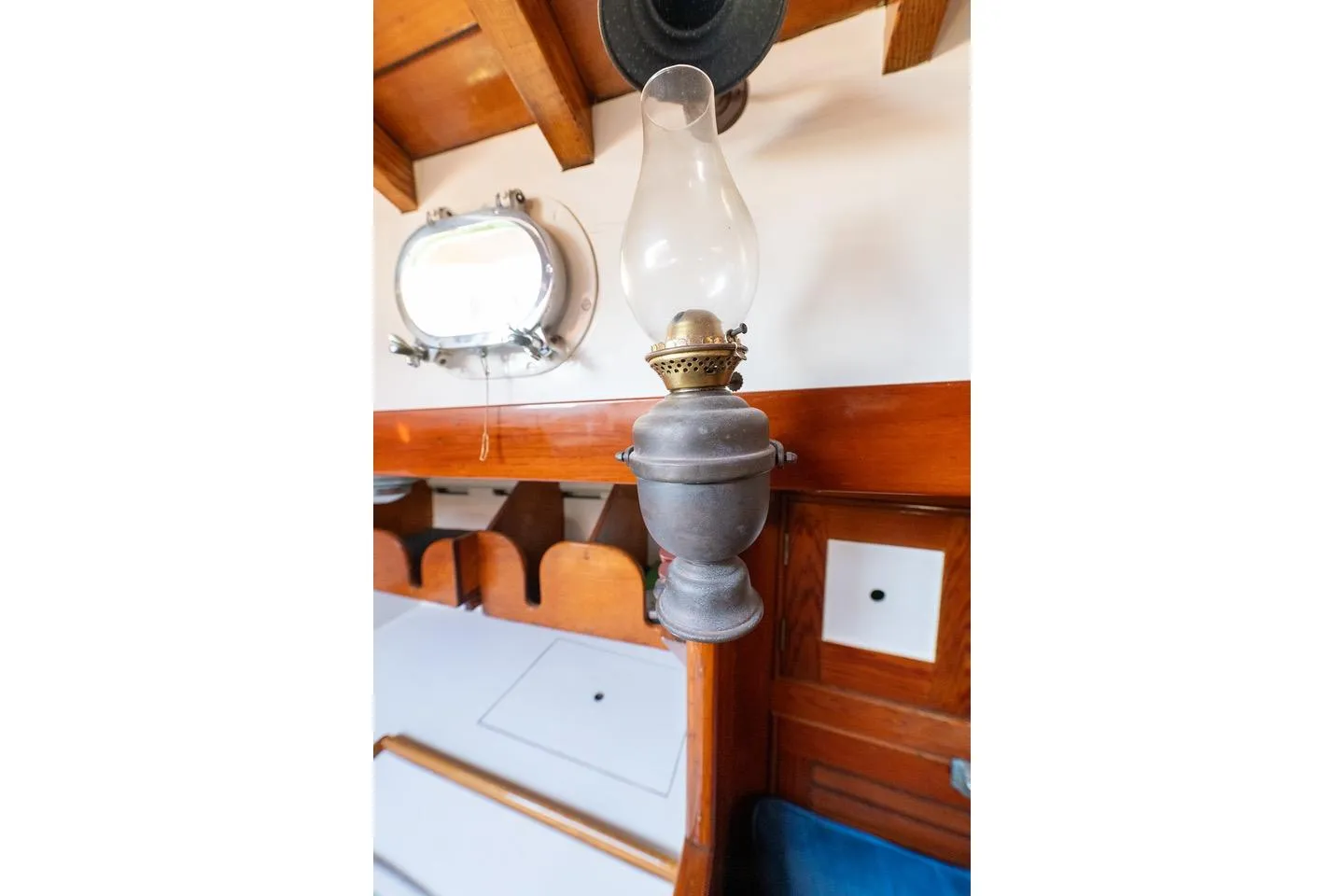 Vintage oil lamp inside 1938 Philip Rhodes Cutter boat cabin, with wooden interior details.