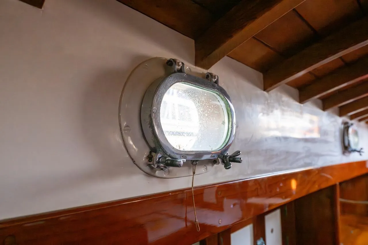 Porthole view inside 1938 Philip Rhodes Cutter, showcasing vintage maritime craftsmanship.