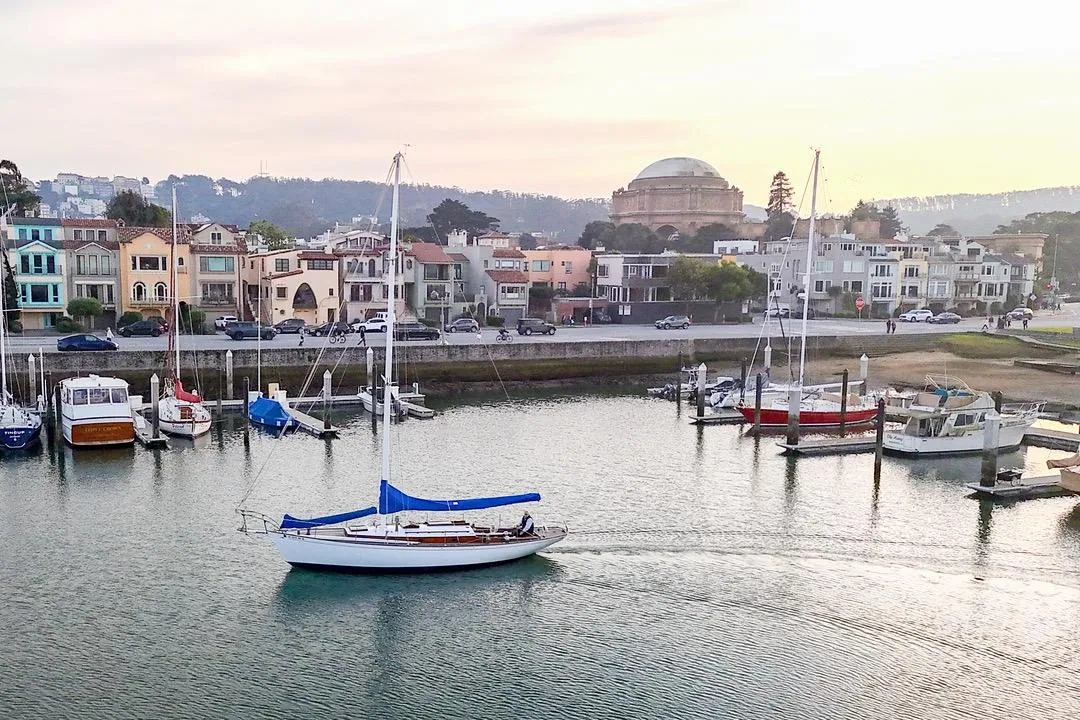Sailboat in marina with colorful houses and dome building, Philip Rhodes Cutter, 1938.