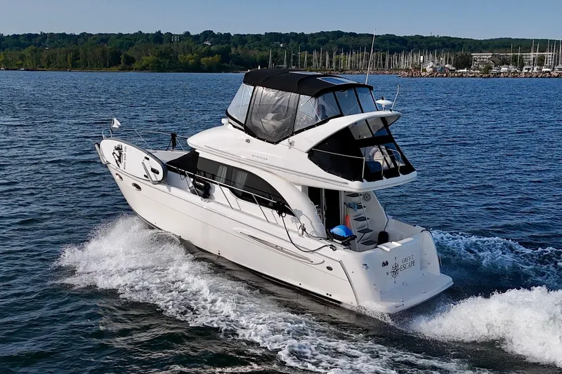  Yacht Photos Pics 2003 Meridian 341 Sedan cruising on a lake with forested shoreline in the background.