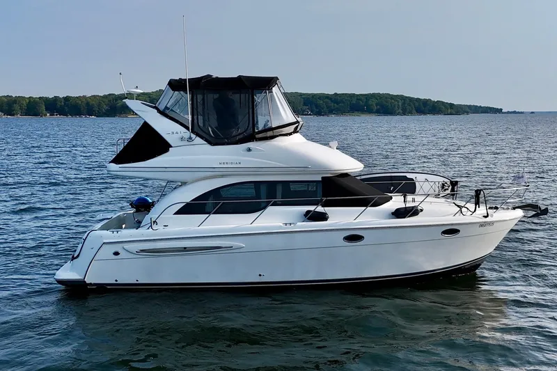  Yacht Photos Pics 2003 Meridian 341 Sedan yacht cruising on a serene lake with lush green shoreline.