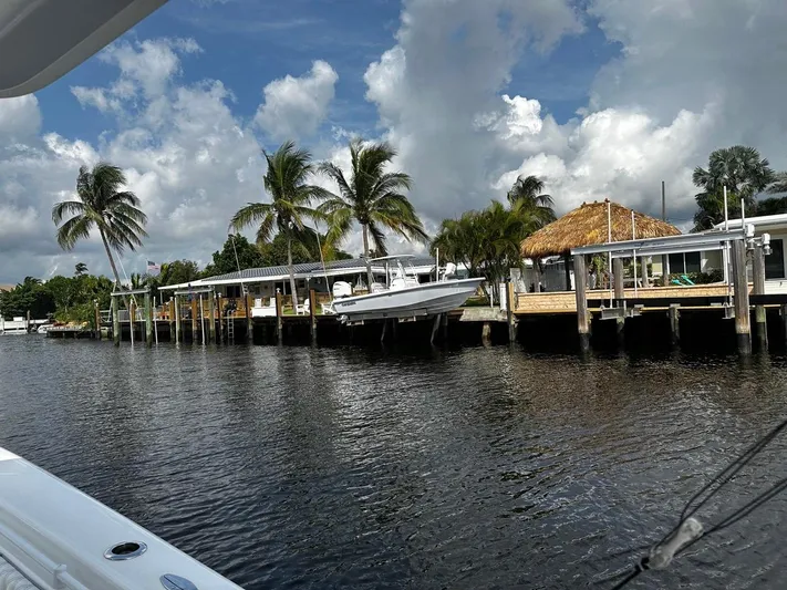  Yacht Photos Pics 2023 Everglades 243 Center Console boat docked by palm trees and waterfront homes.