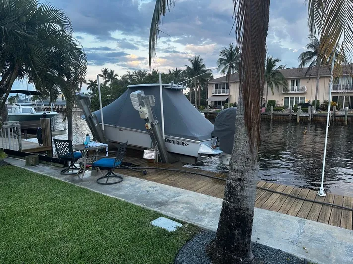  Yacht Photos Pics 2023 Everglades 243 Center Console boat docked by waterfront homes, surrounded by palm trees.
