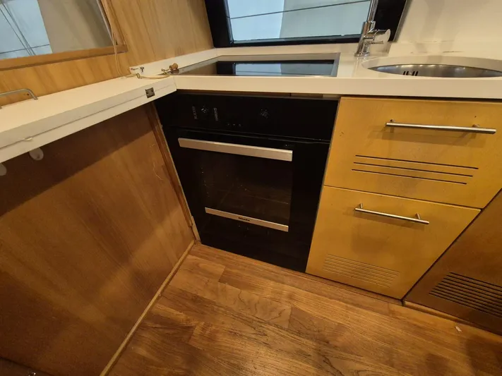  Yacht Photos Pics Compact kitchen area in a 1998 Riva Dolce Vita yacht with modern appliances and wood finish.