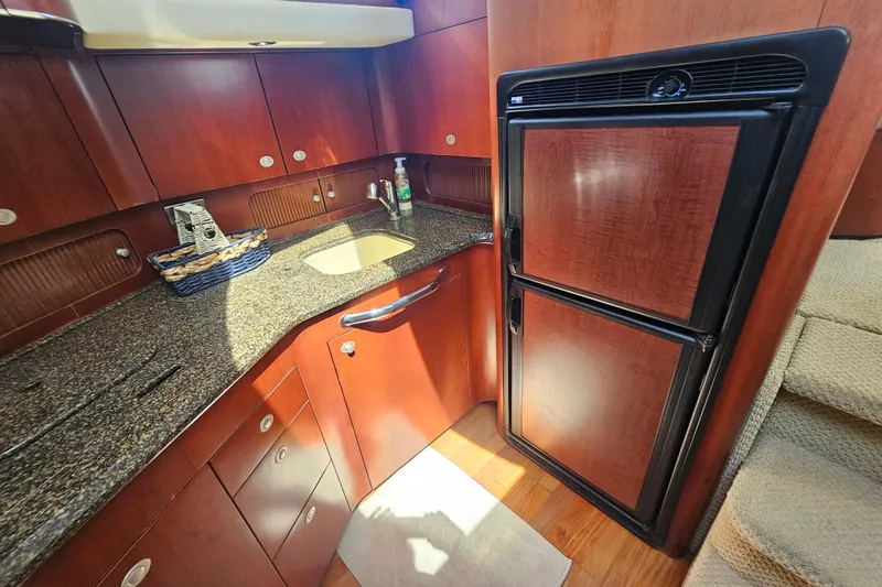 Reflections Yacht Photos Pics 2005 Sea Ray 390 Motor Yacht kitchen with wood cabinetry and compact refrigerator.