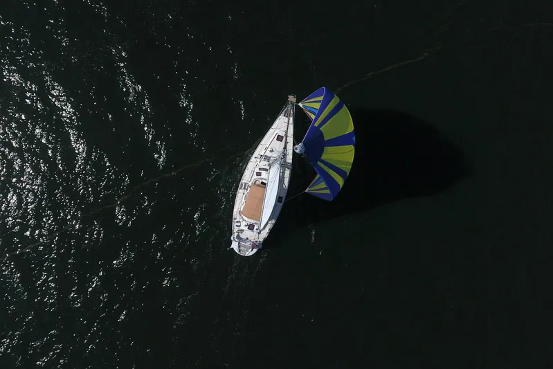Legacy Yacht Photos Pics Aerial view of 2012 Hylas 49CC sailboat with colorful spinnaker on dark water.