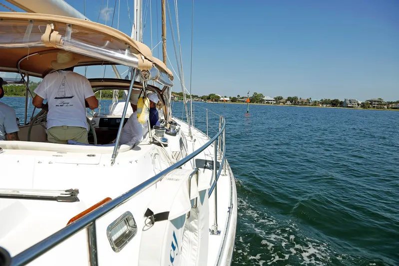 Legacy Yacht Photos Pics Sailing on a 2012 Hylas 49CC yacht near a coastal shoreline under clear blue skies.