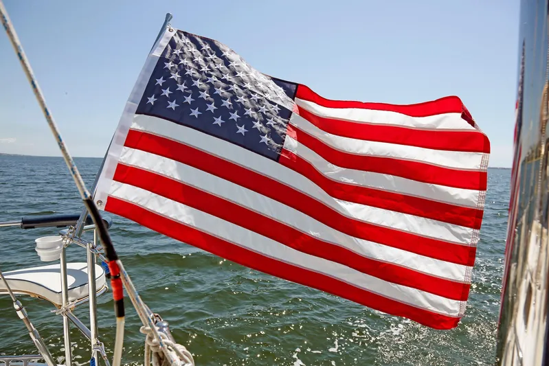 Legacy Yacht Photos Pics American flag waving on a 2012 Hylas 49CC sailboat in open water.