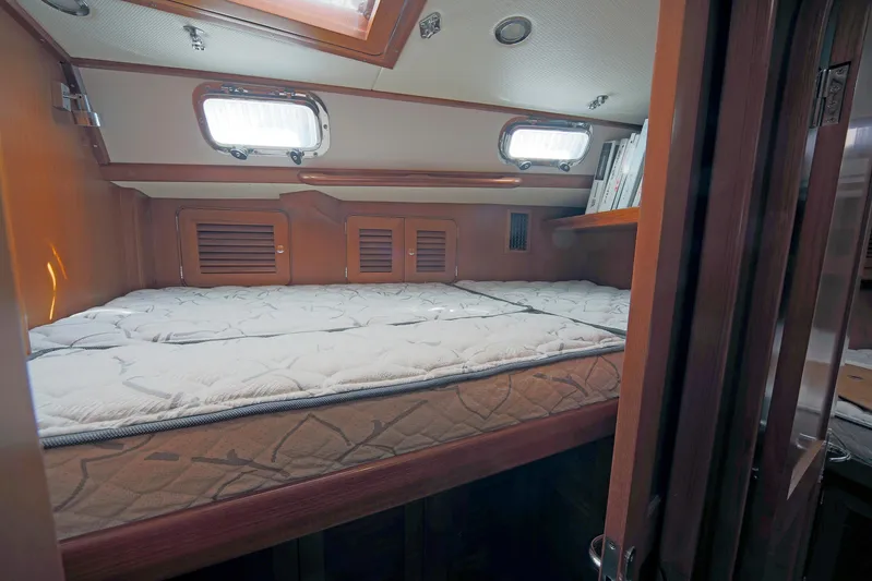 Legacy Yacht Photos Pics Cozy cabin interior of 2012 Hylas 49CC yacht with comfortable bedding and wooden finish.