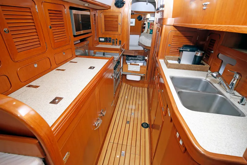 Legacy Yacht Photos Pics Luxurious 2012 Hylas 49CC yacht interior with wooden cabinetry and modern kitchen amenities.