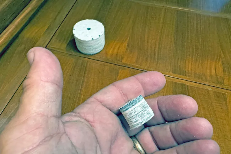 Legacy Yacht Photos Pics Hand holding a small cylindrical object on a wooden surface, Hylas 49CC 2012 model.