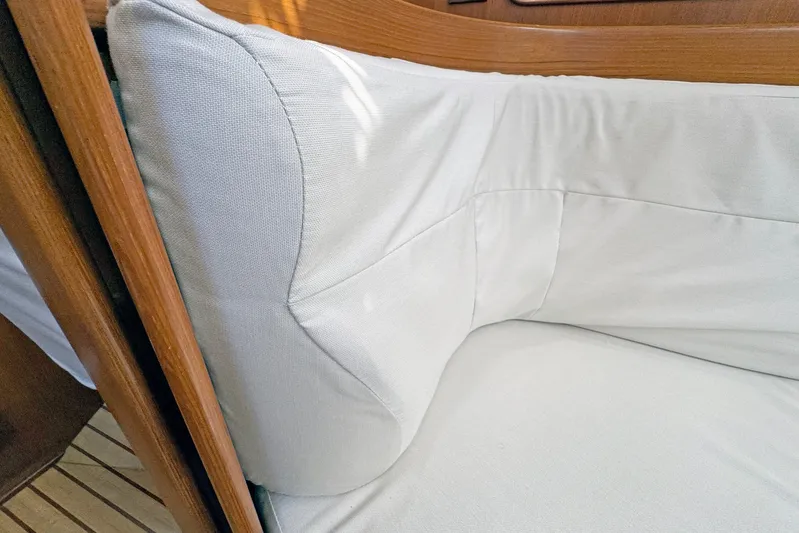 Legacy Yacht Photos Pics Cushioned seating area inside a 2012 Hylas 49CC yacht, featuring light upholstery and wooden trim.