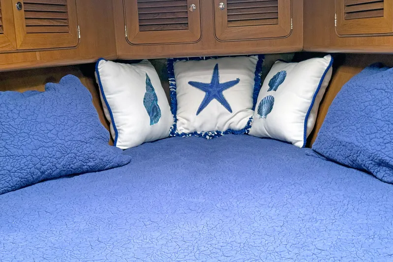 Legacy Yacht Photos Pics Cozy cabin bed with blue quilt and nautical-themed pillows in 2012 Hylas 49CC yacht.