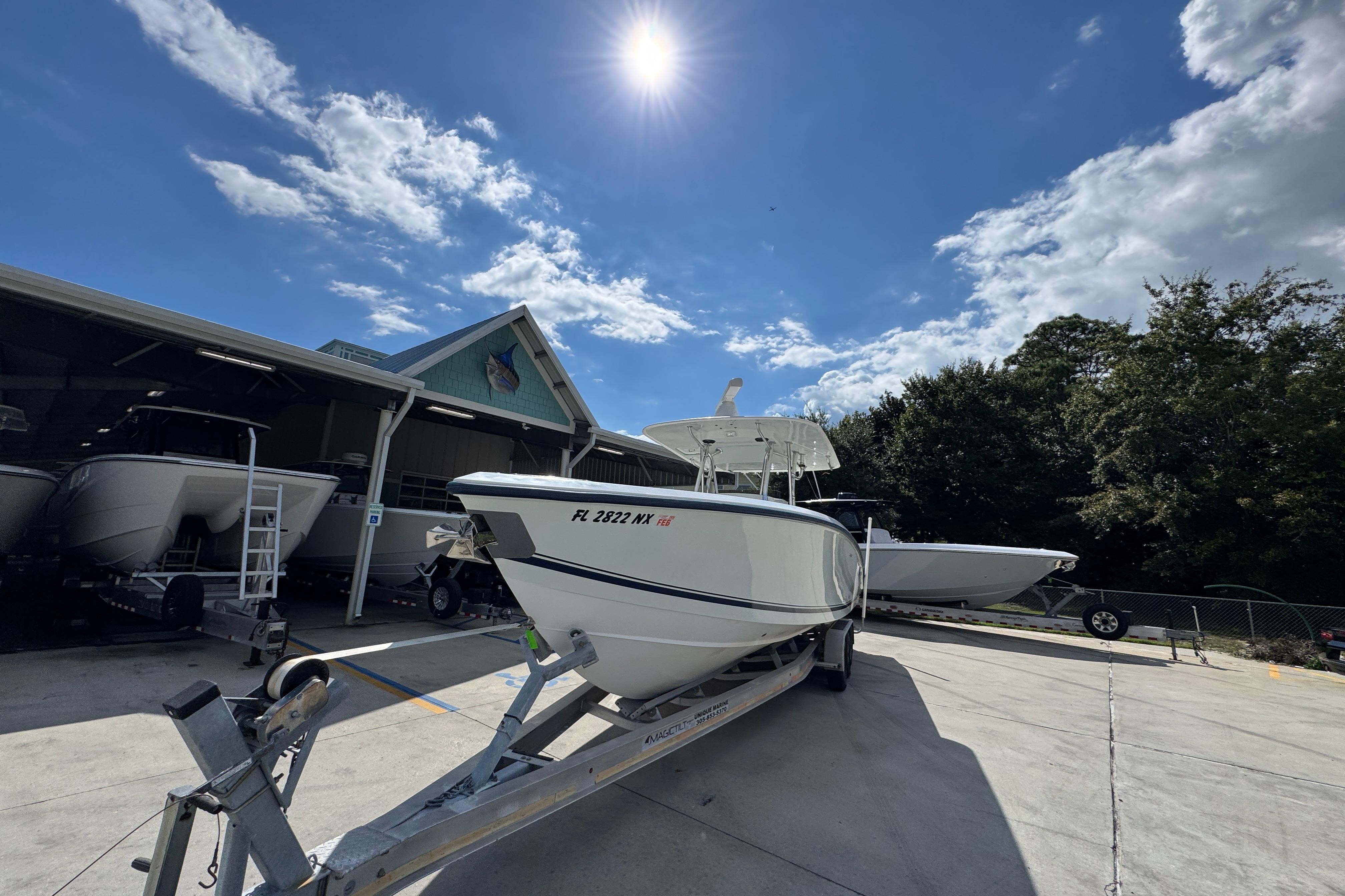 2007 Venture 34 Open boat on trailer under sunny sky, parked near a building.