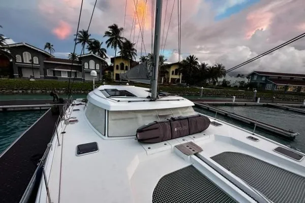 Kaikira Yacht Photos Pics 2019 Nautitech 46 catamaran docked at marina, with sunset sky and palm trees.
