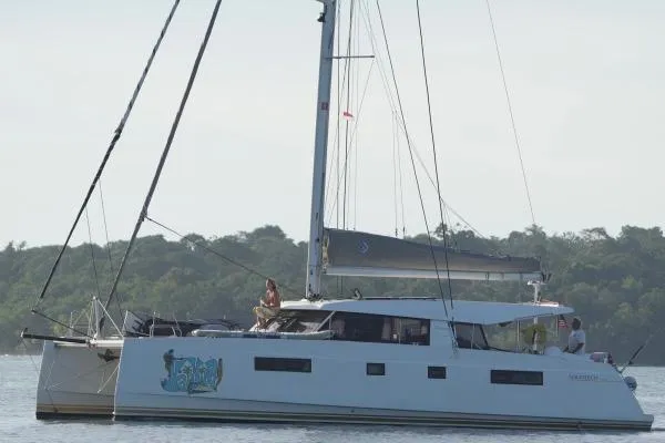 Kaikira Yacht Photos Pics 2019 Nautitech 46 catamaran sailing near lush green shoreline.