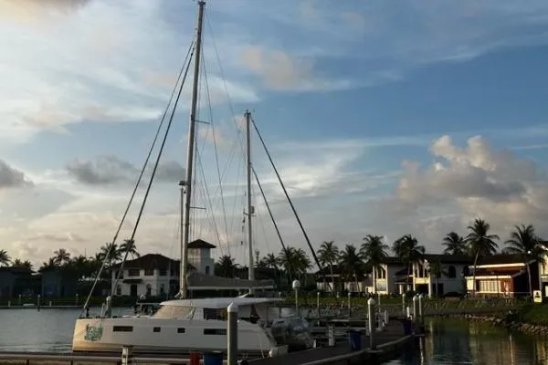 Kaikira Yacht Photos Pics 2019 Nautitech 46 catamaran docked at a marina with palm trees and houses.