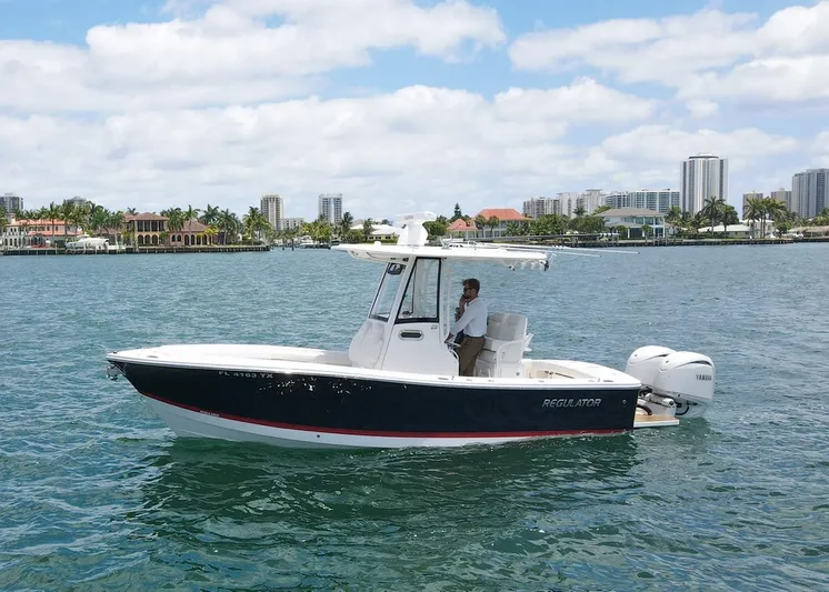  Yacht Photos Pics 2024 Regulator 23 boat on water, city skyline in background, clear sky.