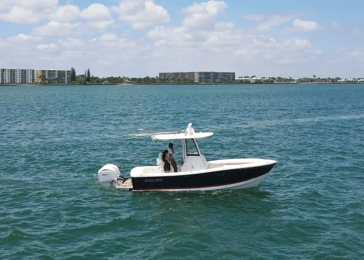  Yacht Photos Pics 2024 Regulator 23 boat cruising on a sunny day with buildings in the background.