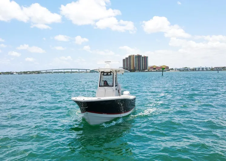  Yacht Photos Pics 2024 Regulator 23 boat cruising on open water with cityscape in background.