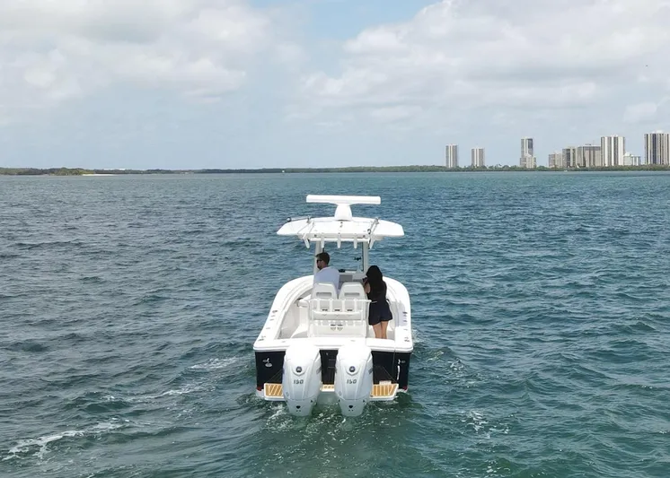  Yacht Photos Pics 2024 Regulator 23 boat cruising on open water with city skyline in background.