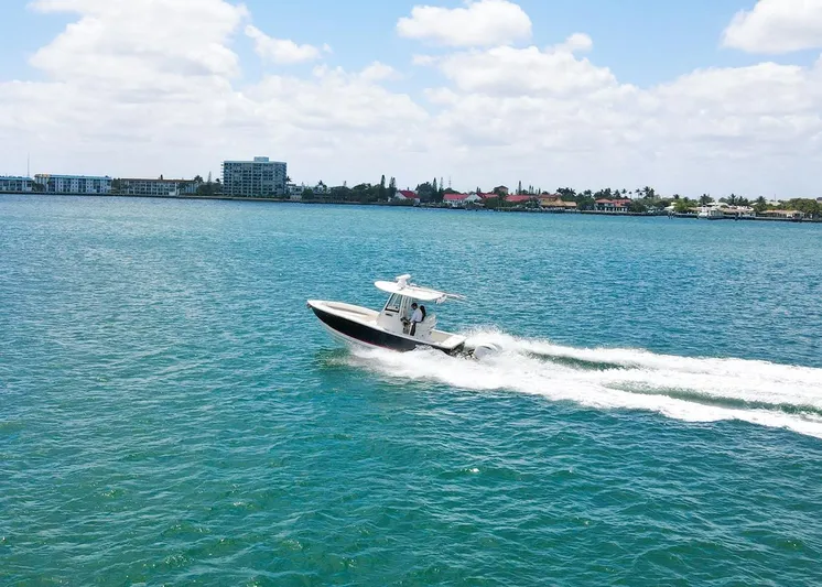  Yacht Photos Pics 2024 Regulator 23 boat cruising on blue water under a partly cloudy sky.