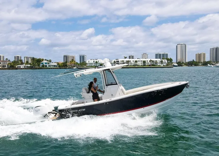  Yacht Photos Pics 2024 Regulator 23 boat cruising on water with city skyline in background.