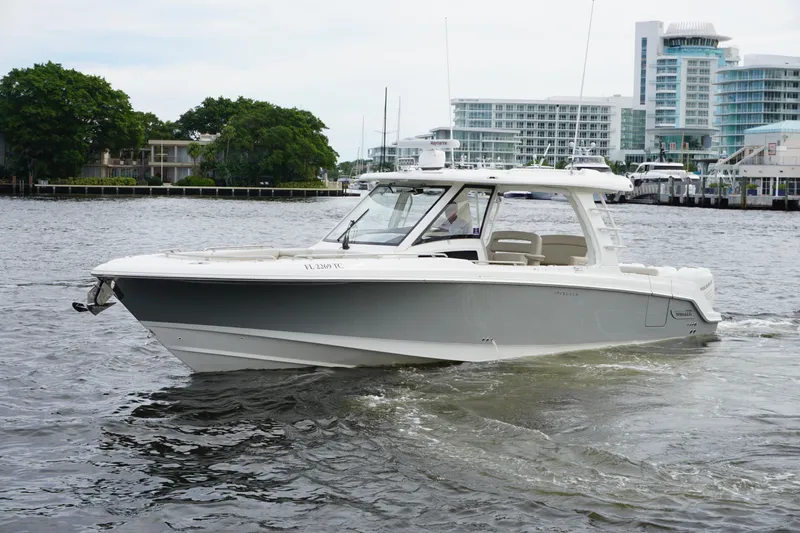 Iboat 3 Yacht Photos Pics 2019 Boston Whaler 350 Realm cruising on a river near modern buildings.