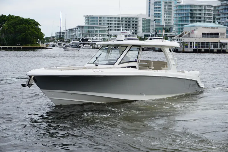 Iboat 3 Yacht Photos Pics 2019 Boston Whaler 350 Realm boat cruising in a marina with modern buildings.