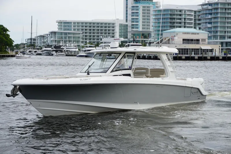 Iboat 3 Yacht Photos Pics 2019 Boston Whaler 350 Realm boat cruising near modern waterfront buildings.