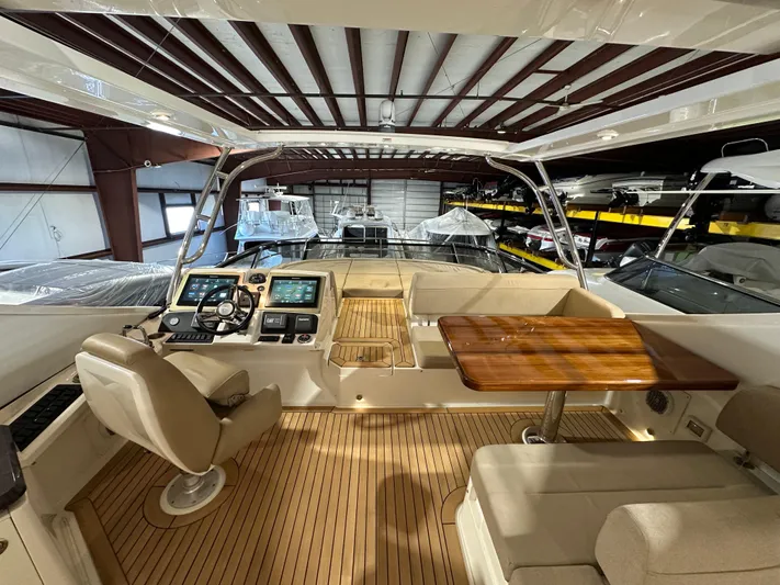 Flawless Yacht Photos Pics 2015 Sea Ray L650 Flybridge interior with helm, seating, and wooden table in a boat storage facility.