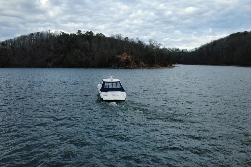  Yacht Photos Pics Sea Ray Sundancer 460 (2004) cruising on a serene lake with wooded shoreline.