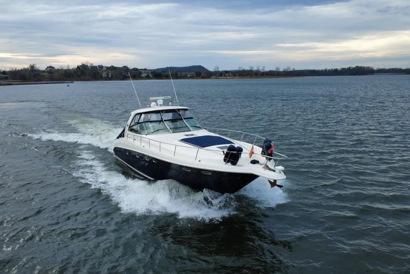  Yacht Photos Pics 2004 Sea Ray Sundancer 460 cruising on a serene lake under a cloudy sky.