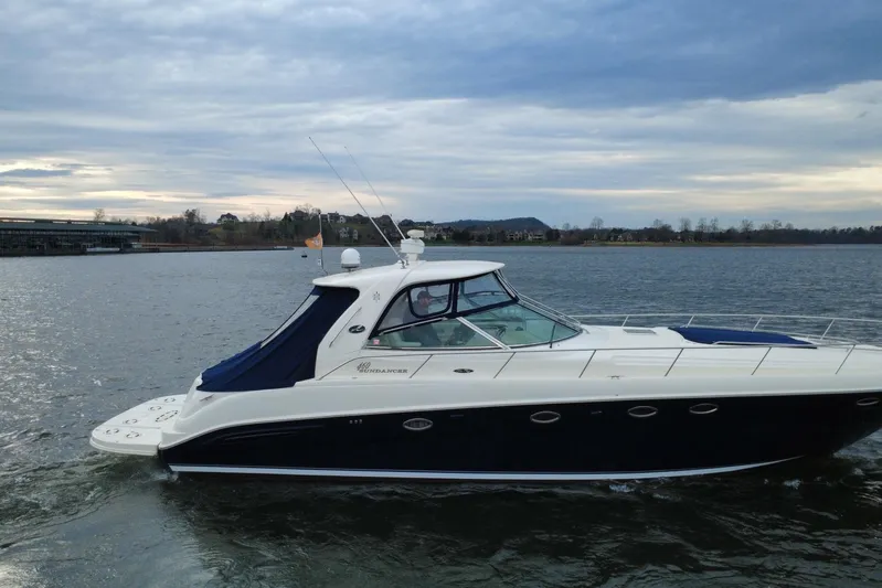  Yacht Photos Pics 2004 Sea Ray Sundancer 460 yacht cruising on a serene lake under a cloudy sky.