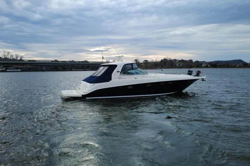  Yacht Photos Pics 2004 Sea Ray Sundancer 460 yacht cruising on a calm lake under a cloudy sky.