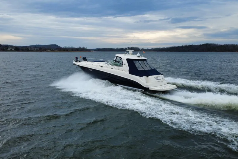  Yacht Photos Pics 2004 Sea Ray Sundancer 460 cruising on a lake under a cloudy sky.