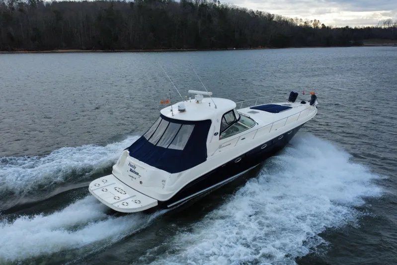  Yacht Photos Pics 2004 Sea Ray Sundancer 460 cruising on a serene lake with forested shoreline.