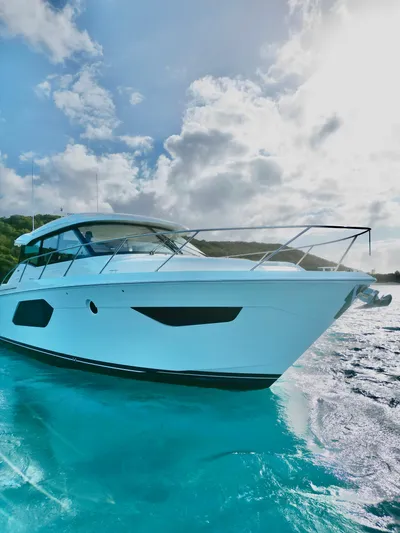  Yacht Photos Pics 2023 Tiara Yachts C49 Coupe cruising on clear blue water under a cloudy sky.