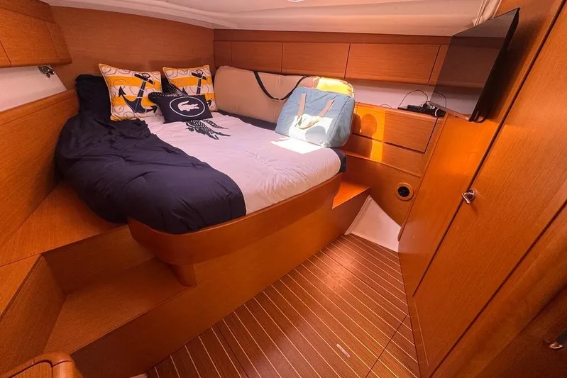  Yacht Photos Pics Cozy cabin interior of 2011 Jeanneau 50 Deck Saloon with bed and TV.