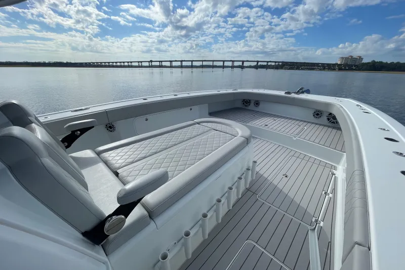  Yacht Photos Pics Luxurious 2022 Freeman 47 boat interior with cushioned seating, overlooking calm waters and a bridge.